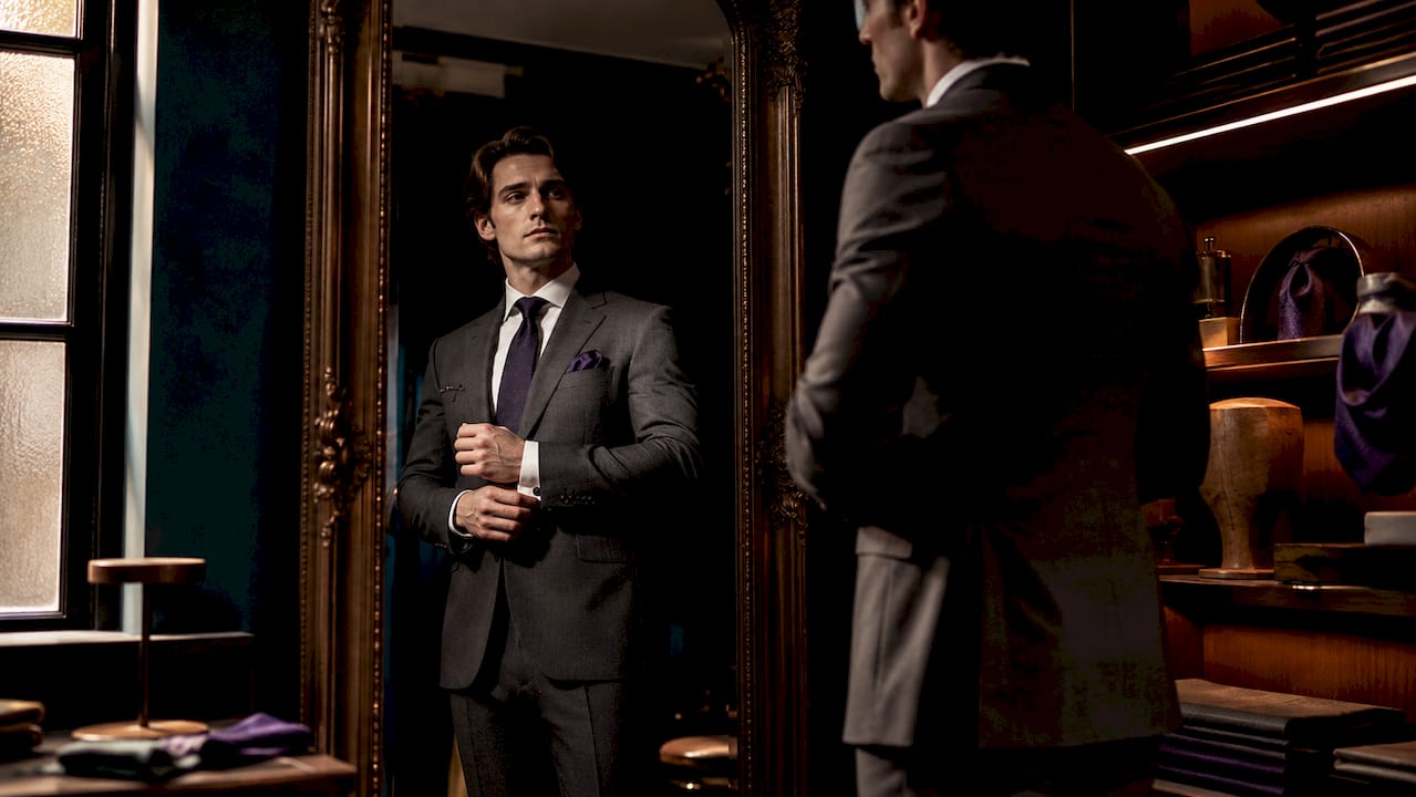 Man adjusting tailored suit cufflinks in boutique fitting room