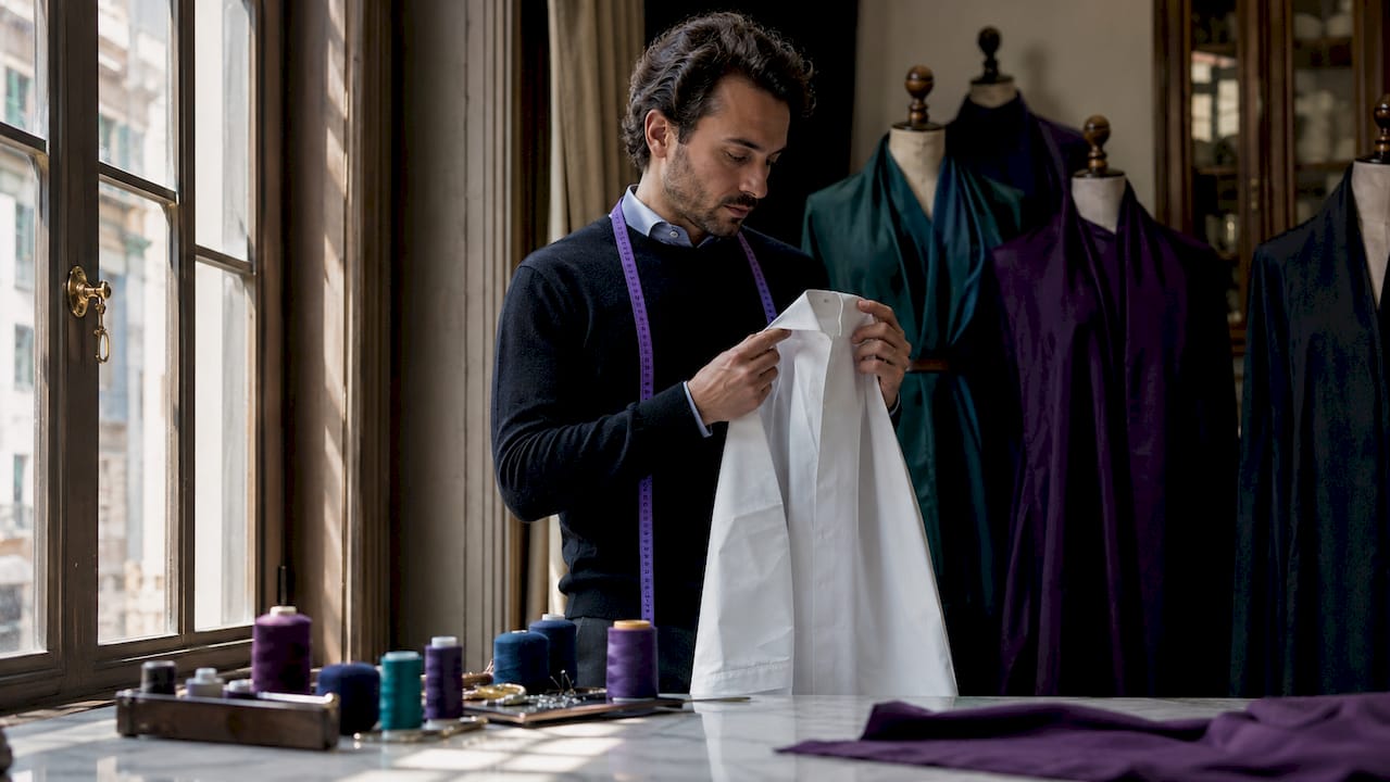 Male stylist inspecting dress shirt placket