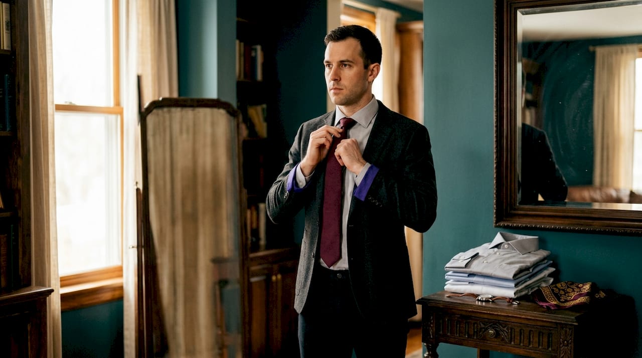 Man adjusting tie against dress shirt in mirror