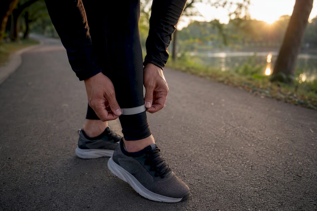 Man adjusting reflective strip on ankle at dusk