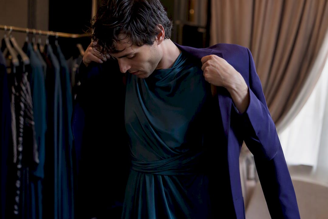 Man layering blazer over dress in boutique dressing room