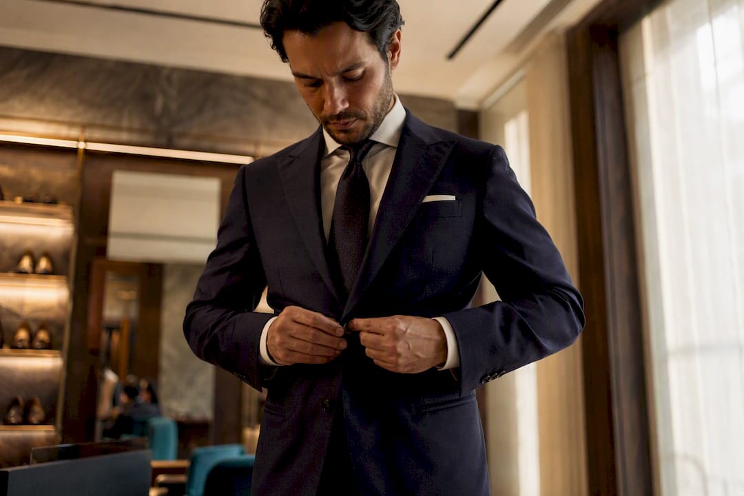 Man fastening top button of suit jacket