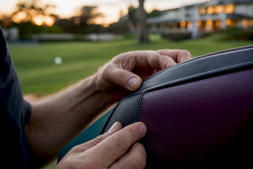 Craftsman's hands examining golf bag welded seam